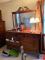 Front view of wooden dresser with multiple drawers and mirror showing some scratches and surface wear.
