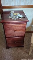Front view of the two-drawer wooden file cabinet, showing surface wear and wood grain pattern