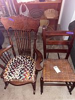 Photo showing two vintage rocking chairs side by side; left chair with carved wood back and multicolored braided woven seat, right chair with simpler wood back and straw woven seat.