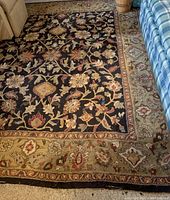 Close-up view of central field and border of floral design area rug showing pattern detail and wear