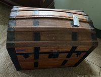 Top view of wooden steamer trunk showing curved top, iron horizontal brackets, and rivets.