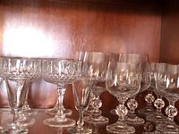 Grouped image of 16 stemware glasses including wine, cordial, and sherbet glasses showing their shape and stem details against wooden background