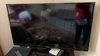 Samsung 40-inch TV on stand with remote control visible on nearby surface.