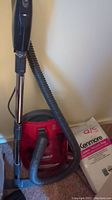 Kenmore red canister vacuum with hose and wand, partial view of vacuum bags