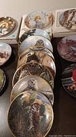 Eight collector plates stacked showing mostly owl artwork with gold rims.