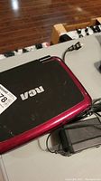 Photo of top surface of RCA portable travel DVD player with power adapter visible and cable connected.