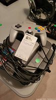 Gray Nintendo 64 console with gray controller and cables on top, two game cartridges partially visible.