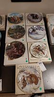 Photo showing seven animal-themed collector plates in cardboard holders, arranged on a table.