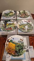 Five decorative plates arranged on boxes showing various bird and nature scenes
