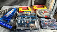 Photo of multiple hand tools including wrenches, socket accessories, and Dremel bits organized in plastic cases