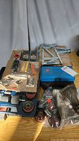 Photo showing entire lot with screwdriver bits, levels, iron furniture feet, drill hole saws, and storage cases spread on a surface.