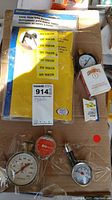 Photo of yellow BraceCraft Lever Style Tuba Bender gloves, pressure gauges, and small boxed parts included in the lot.