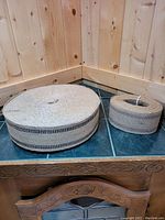 Two rolls of burlap fabric displayed on a countertop with wooden panel walls in the background. One large roll and one smaller roll. 