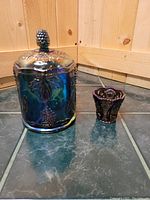 Both items placed on tiled floor against wood panel background: covered compote and toothpick holder.