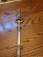 Full view of ceremonial sword laid on wooden table showing overall length and condition