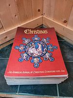 Stack of vintage Christmas books with red cover featuring stained glass nativity scene, 1960s-70s era.