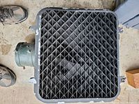 Top view showing black grid pattern inside the housing with metal mounting points and attached cylindrical wiring conduit