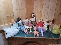 Photo of various dolls including porcelain, cloth, and plastic dolls with different outfit styles and sizes