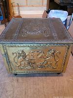 Front view of the fireplace box showing embossed metal design with two lions and crest on front.