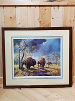Full frontal view of framed buffalo art print by Hulan Fleming against wood background.
