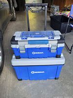 Front view of two stacked blue and gray Kobalt tool boxes with handle extended, showing metal latches on the top box and wheels on the base box.