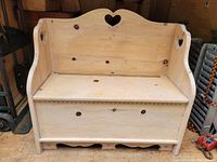 Front view of the wooden porch bench showing heart cutout on backrest and storage compartment under the seat.