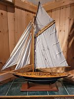 Front and side view of the wooden sailing ship model on a display stand showing sails and deck details.