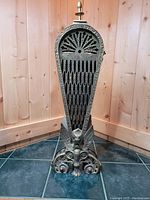 Front view of a single panel of the brass fireplace screen showing detailed cut-out work and ornamental base.