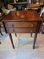 Front view of Willett drop leaf side table showing two drawers and turned legs.