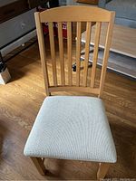 Front view of a blonde wood chair showing the slatted back and upholstered seat.