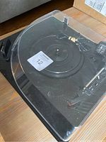 Top angle showing the entire turntable with clear dust cover and power adapter cable.