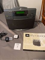 JBL Harmony powered radio with remote, Bluetooth adapter, power adapter, and manual booklet on a table.