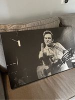 Photo of the black and white Johnny Cash poster displayed on a couch, showing the full poster with minor corner wear.