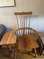 Front view of the wooden Queen Anne style chair showing the seat, pull-out writing surface with drawer, and backrest with vertical spindles.