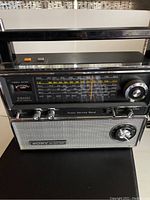 Front view of Sony TFM-8000W multi-band radio showing tuning dial, tuning meter, power switch, volume and tone controls, and built-in handle.