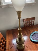 Full view of the vintage tall brass lamp showing its height and glass shade.