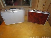 Both cases shown side by side on wooden surface; silver padded case on left and vintage briefcase on right