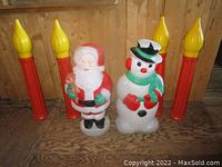Full view of Santa, Snowman and four candles against plywood background