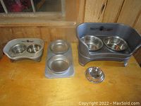 Photo of multiple Neater Feeder elevated dog feeders with stainless steel bowls placed on a wooden surface.