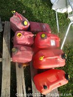 Lot showing six red plastic gas cans on a wooden pallet.