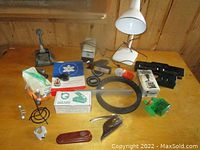 Photo showing various office supplies including label makers, hole punches, stamp, tape rolls, metal ruler, and small tools.