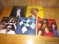 Five vinyl records on a wooden surface, three Steve Martin albums, one Panorama album and one Ramones album.