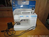 Euro-Pro X white sewing machine with foot pedal and cord on wooden table, original box behind.