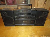 Front view of the Sony stereo system with two speakers placed on either side, showing the overall layout including CD player on top and cassette deck below