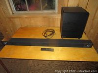 Full view of the Klipsch soundbar, subwoofer, power cable, and remote laid out on a wooden table.