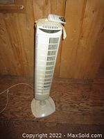 Full view of the white Seville Classics tower fan standing on a wooden surface, showing its upright design and ventilation grille.