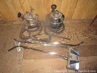 Two Filter Queen vacuums and various parts including hoses, metal wands, and cleaning heads seen from front on wooden floor.