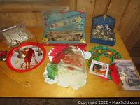 Wide view of the Christmas decorations assortment on wooden table showing Santa face, bird ornaments, wreaths, books, and nativity scene.