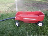 Red Radio Flyer wagon with a wide wagon bed, two axles, handle for pulling, and four wheels on grass.