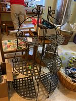 Two metal corner shelving units with lattice shelves and scrollwork, showing wear and rust.